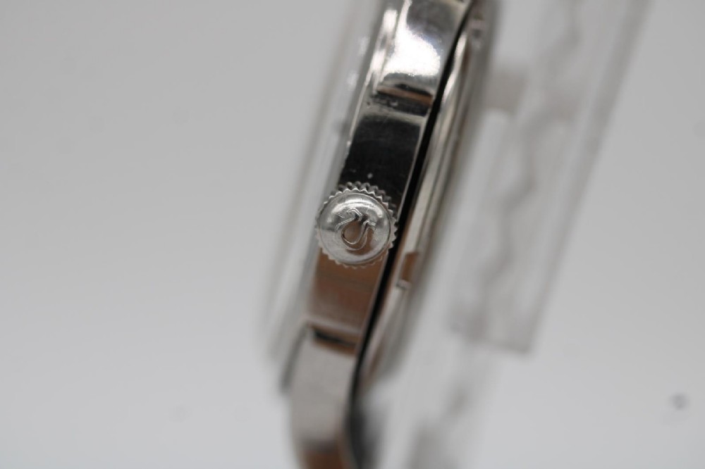 A round 1947 stainless steel Omega wristwatch displaying an aged cream dial with Arabic numerals and fitted with a black textured leather strap. View VIII