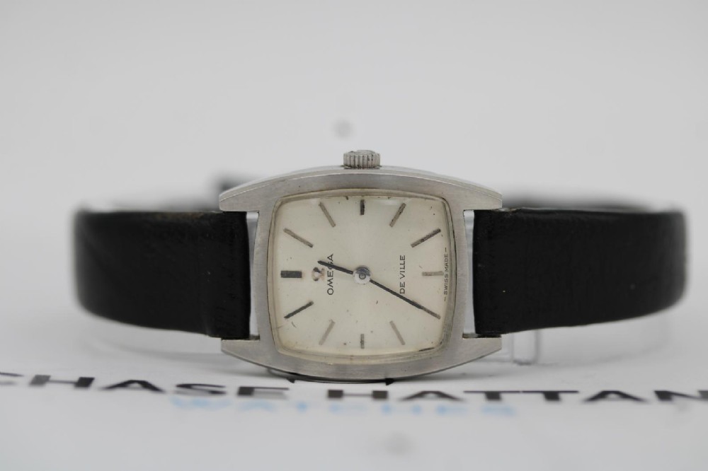 A vintage 1968 ladies Omega De Ville stainless steel wristwatch featuring a tonneau-shaped case, silvered dial, and black leather strap. View III