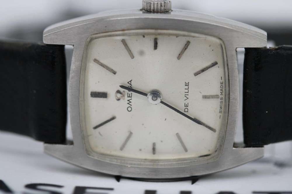 A vintage 1968 ladies Omega De Ville stainless steel wristwatch featuring a tonneau-shaped case, silvered dial, and black leather strap. View IV
