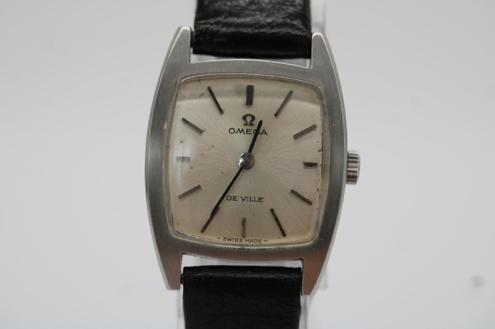 A vintage 1968 ladies Omega De Ville stainless steel wristwatch featuring a tonneau-shaped case, silvered dial, and black leather strap. View VIII