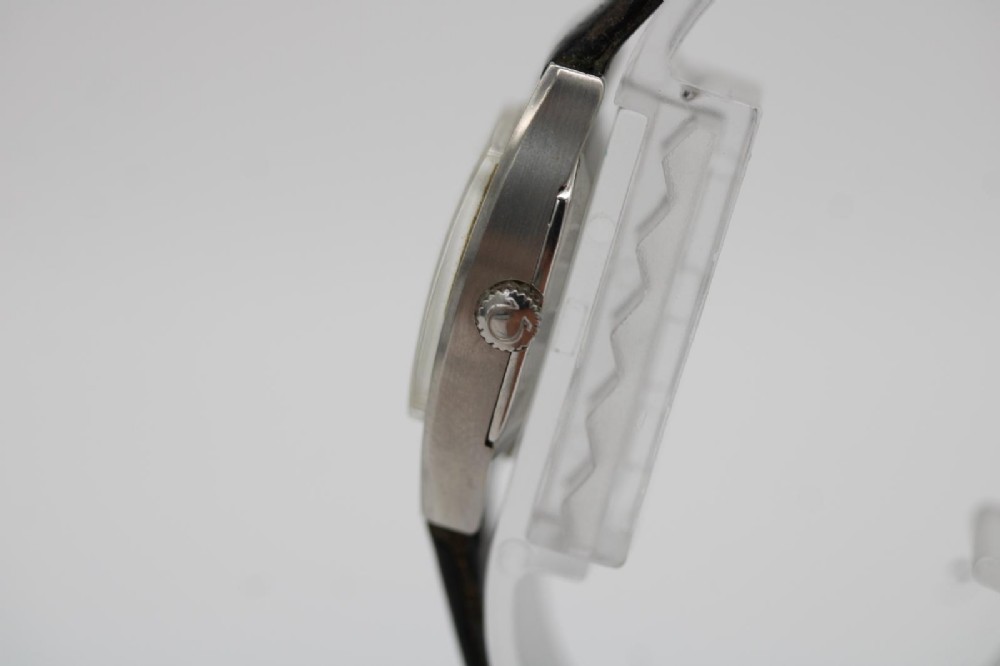 A vintage 1968 ladies Omega De Ville stainless steel wristwatch featuring a tonneau-shaped case, silvered dial, and black leather strap. View IX