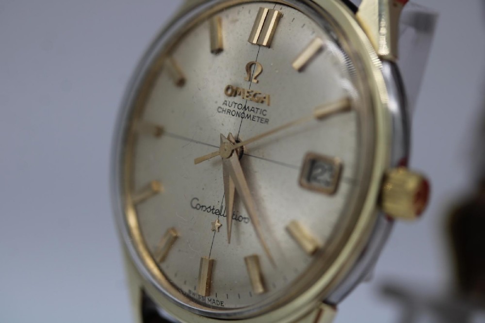 A 1962 vintage Omega Constellation wristwatch featuring a gold pie-pan dial, date aperture, and brown leather strap. View VIII