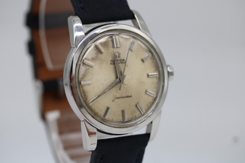 A 1950s stainless steel Omega Seamaster wristwatch featuring a patinated cream dial with silver baton indices and a black leather strap. View III
