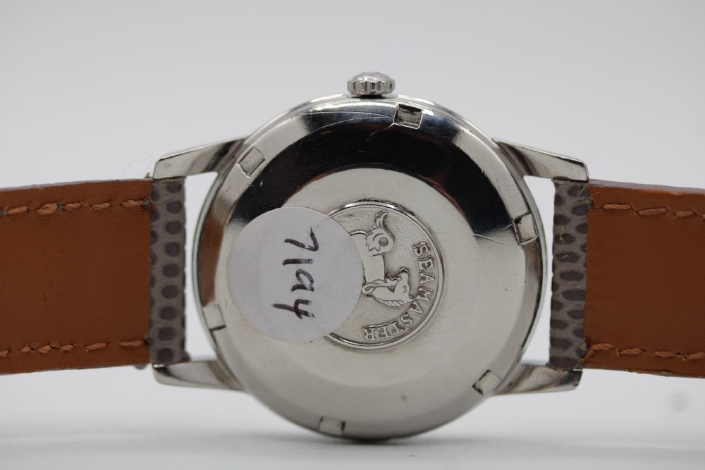 A vintage 1960 Omega Seamaster automatic wristwatch with a stainless steel case, silver cream dial, and grey textured leather strap. View IX