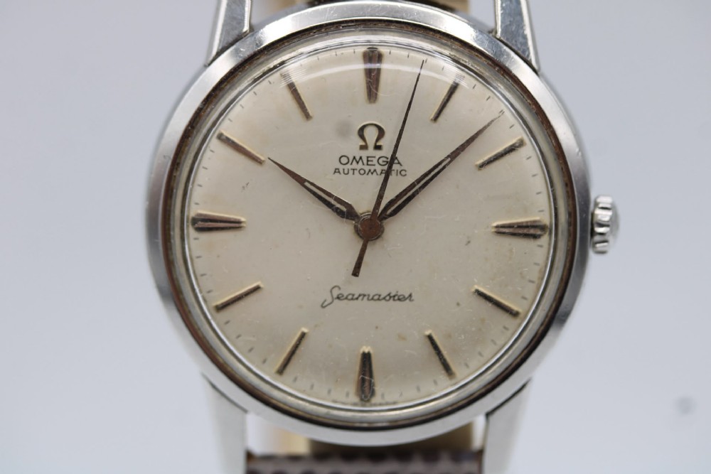 A vintage 1960 Omega Seamaster automatic wristwatch with a stainless steel case, silver cream dial, and grey textured leather strap. View X