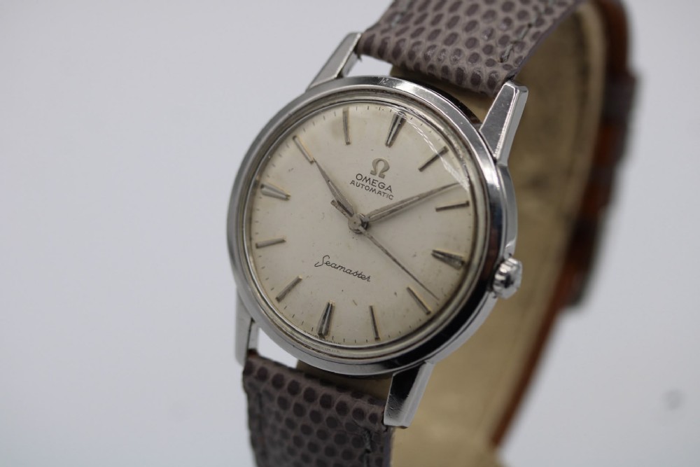 A vintage 1960 Omega Seamaster automatic wristwatch with a stainless steel case, silver cream dial, and grey textured leather strap. View XI