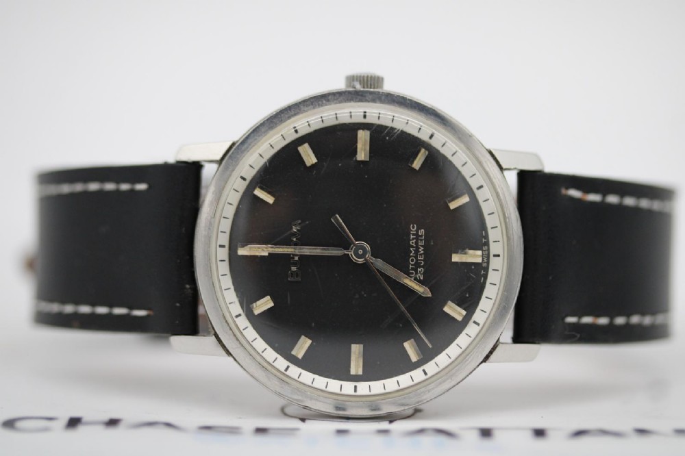 A vintage Bulova automatic wristwatch featuring a black dial with silver baton hour markers and a black leather strap with white stitching. View IX