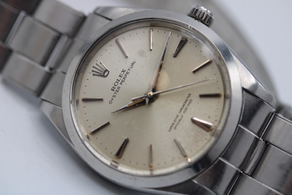 A stainless steel Rolex Oyster Perpetual wrist watch featuring a silver dial with baton indices and an integrated steel bracelet. View V