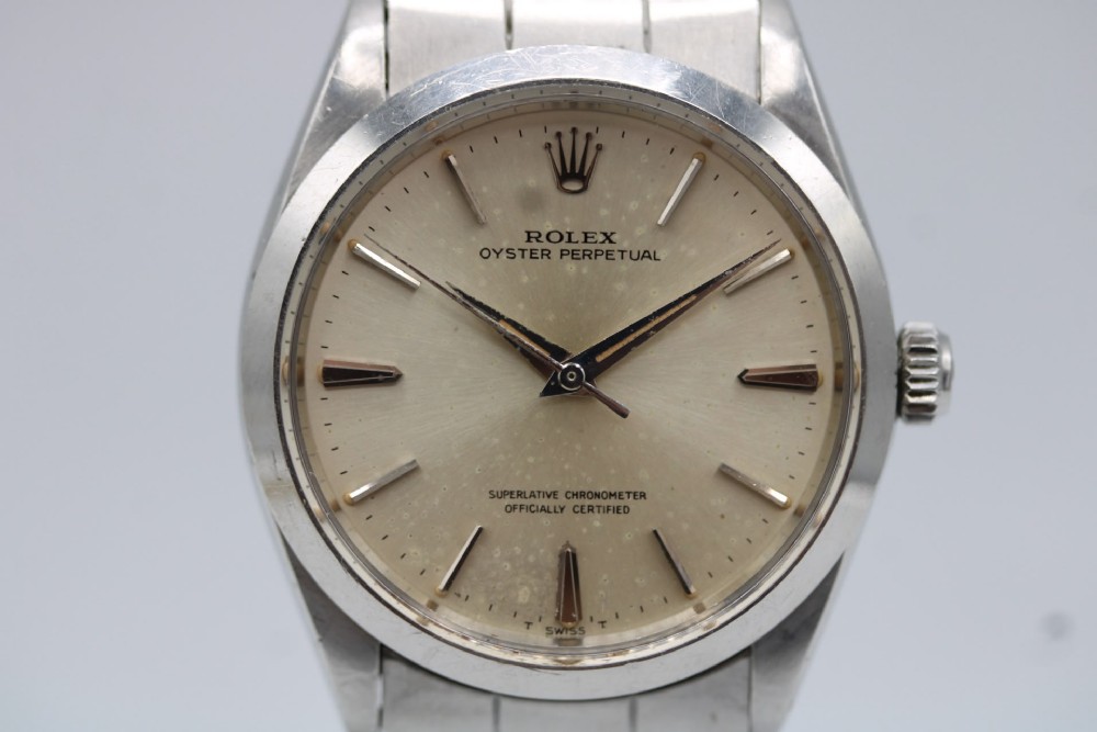 A stainless steel Rolex Oyster Perpetual wrist watch featuring a silver dial with baton indices and an integrated steel bracelet. View VII