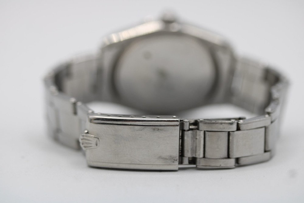 A stainless steel Rolex Oyster Perpetual wrist watch featuring a silver dial with baton indices and an integrated steel bracelet. View XIV