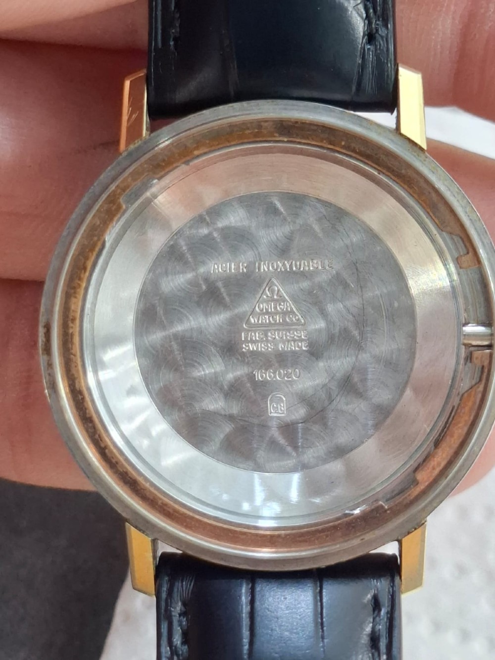 A vintage gold-plated Omega Seamaster DeVille automatic wristwatch with a white textured dial, gold baton indices, date window, and black leather strap. View XIV
