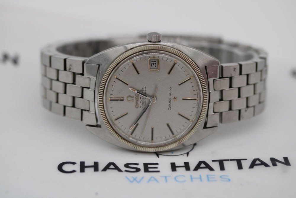 A 1969 vintage Omega Constellation wristwatch featuring a stainless steel case, fluted bezel, silver linen dial, date window, and steel link bracelet.