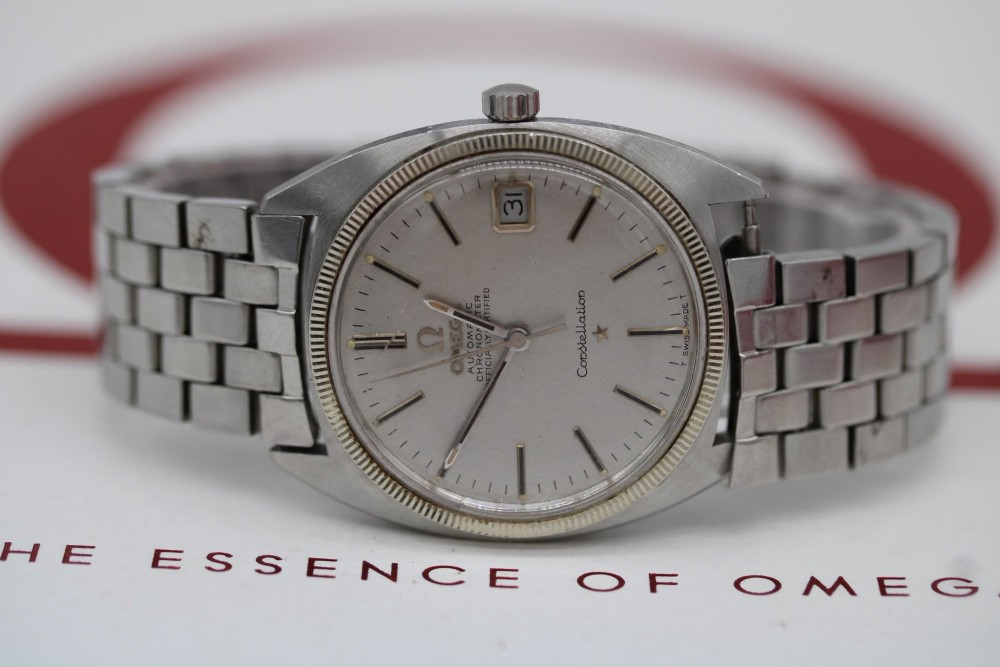 A 1969 vintage Omega Constellation wristwatch featuring a stainless steel case, fluted bezel, silver linen dial, date window, and steel link bracelet. View III