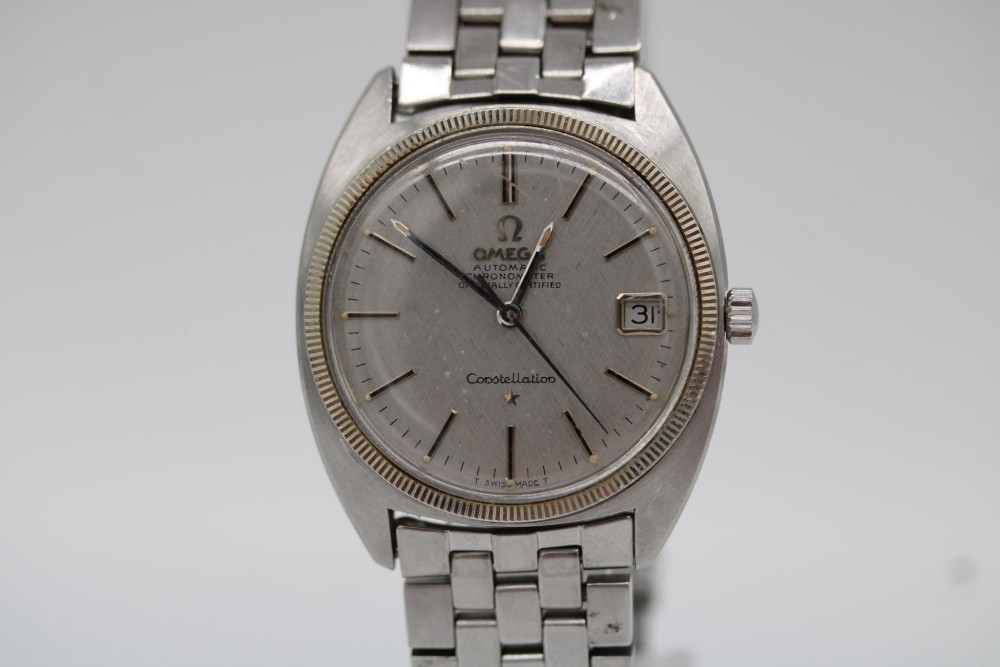A 1969 vintage Omega Constellation wristwatch featuring a stainless steel case, fluted bezel, silver linen dial, date window, and steel link bracelet. View IV