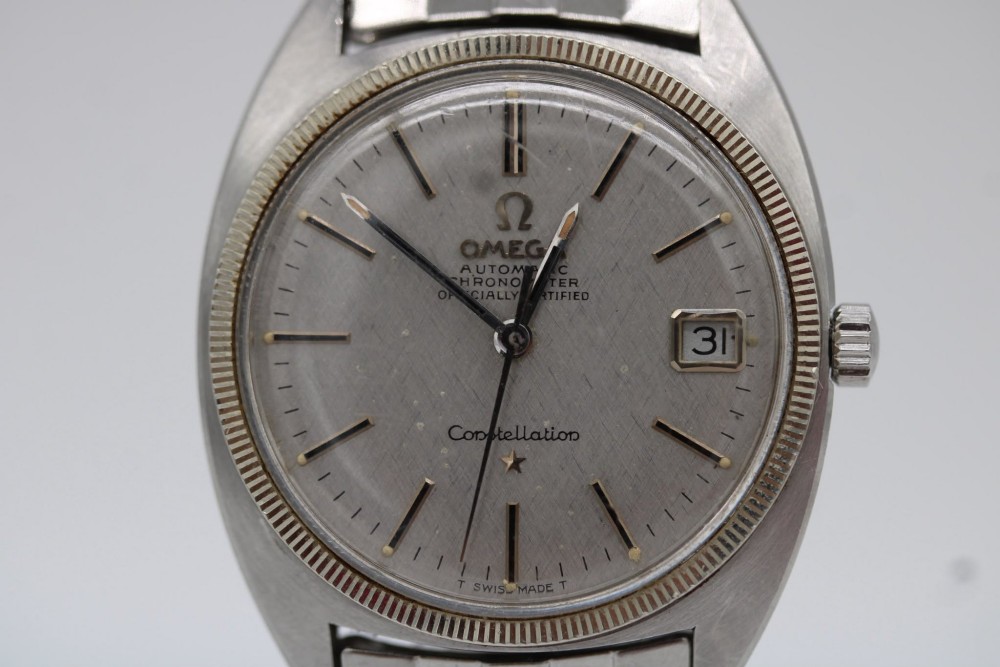 A 1969 vintage Omega Constellation wristwatch featuring a stainless steel case, fluted bezel, silver linen dial, date window, and steel link bracelet. View V