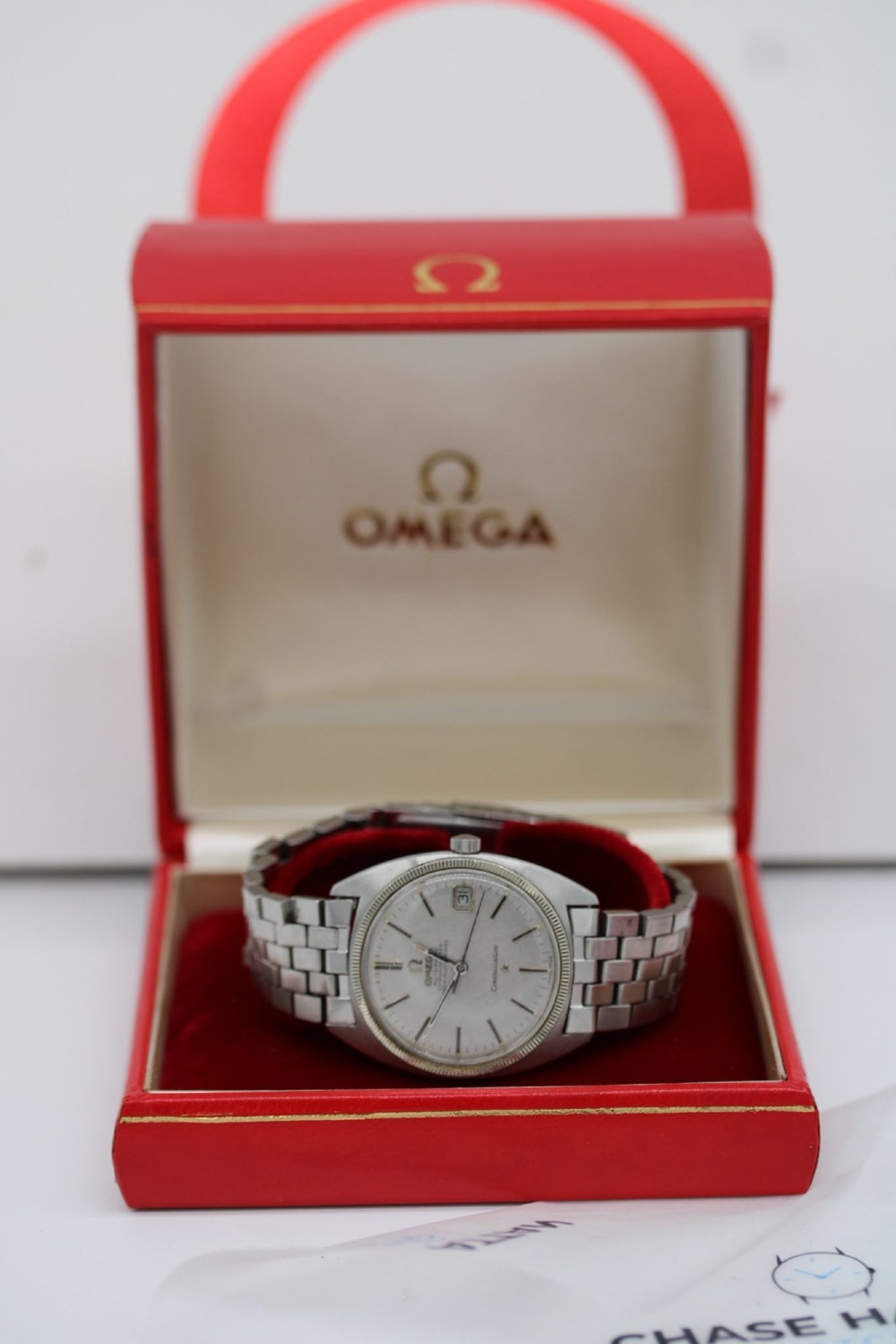 A 1969 vintage Omega Constellation wristwatch featuring a stainless steel case, fluted bezel, silver linen dial, date window, and steel link bracelet. View X