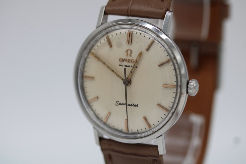 A vintage 1961 Omega Seamaster wristwatch with a stainless steel case, silver dial, applied baton hour markers, and a tan leather strap. View IV