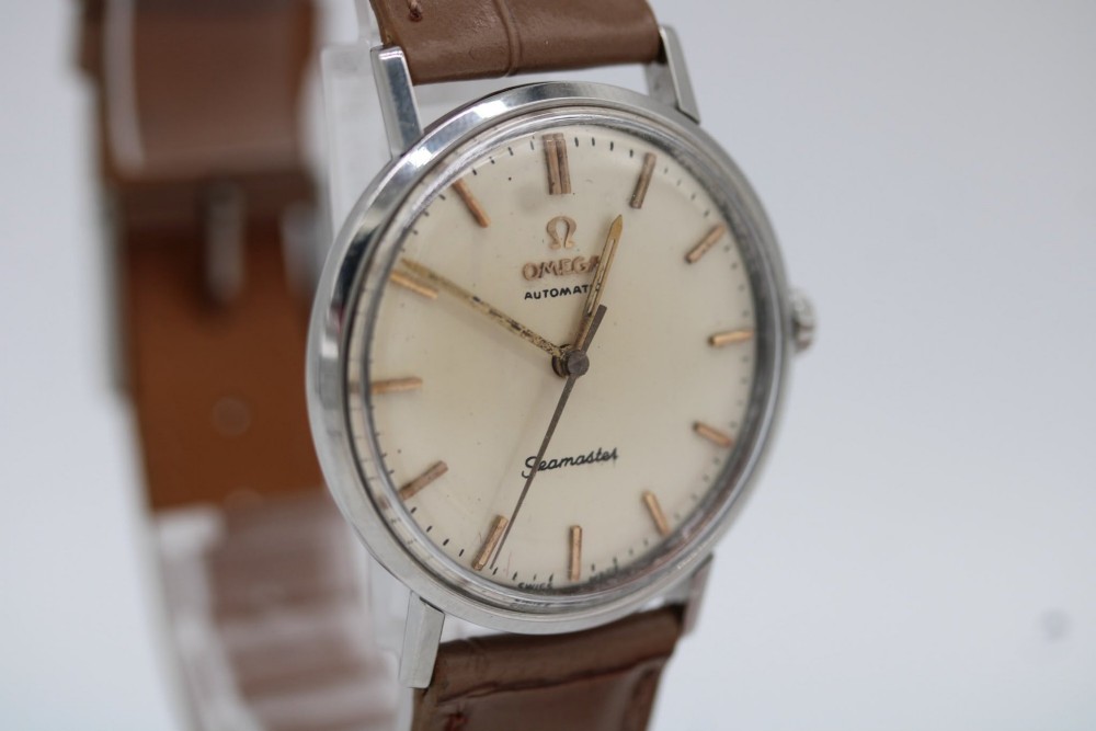 A vintage 1961 Omega Seamaster wristwatch with a stainless steel case, silver dial, applied baton hour markers, and a tan leather strap. View V