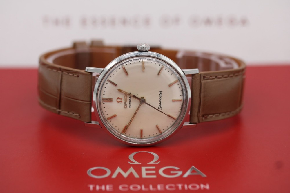 A vintage 1961 Omega Seamaster wristwatch with a stainless steel case, silver dial, applied baton hour markers, and a tan leather strap. View VI