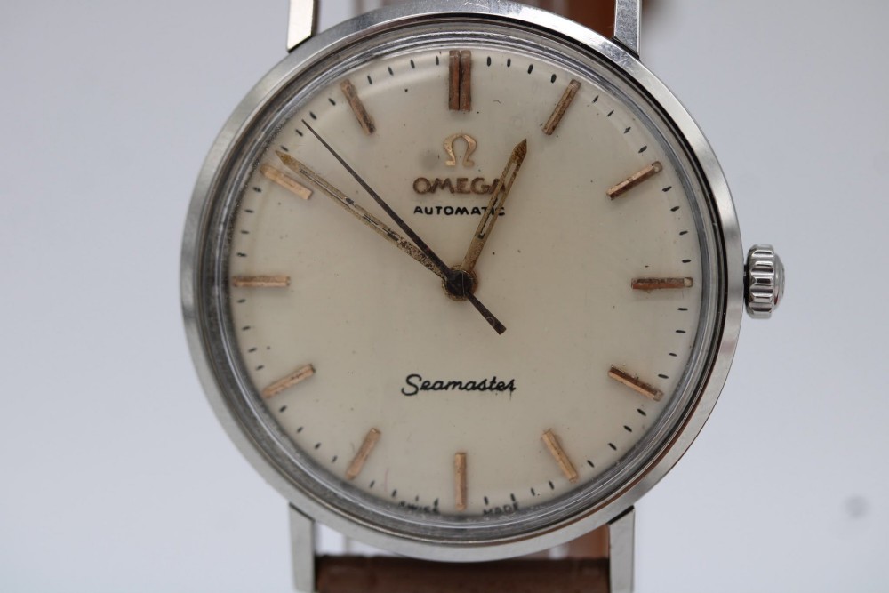 A vintage 1961 Omega Seamaster wristwatch with a stainless steel case, silver dial, applied baton hour markers, and a tan leather strap. View VII