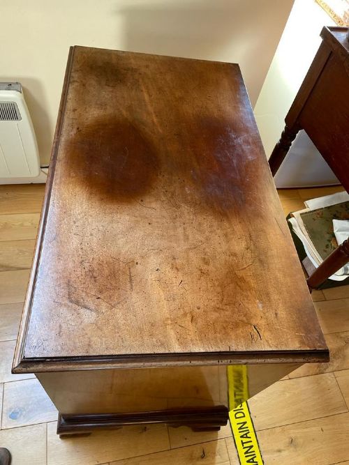 fig 1. A Georgian mahogany kneehole desk featuring multiple small drawers with brass handles, a central recessed cupboard, and a flat timber top.