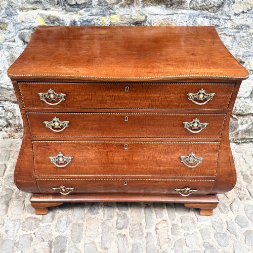 fig 1. A late 18th-century Dutch mahogany chest of drawers featuring a shaped bombee profile, four long drawers with decorative brass handles, and bracket feet.