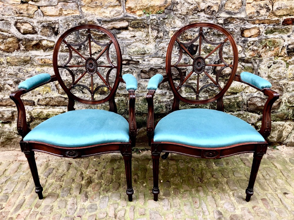 Pair of Sheraton Revival mahogany elbow chairs with oval wheel-back splats, carved rosettes, turquoise velvet seats, and turned reeded front legs.