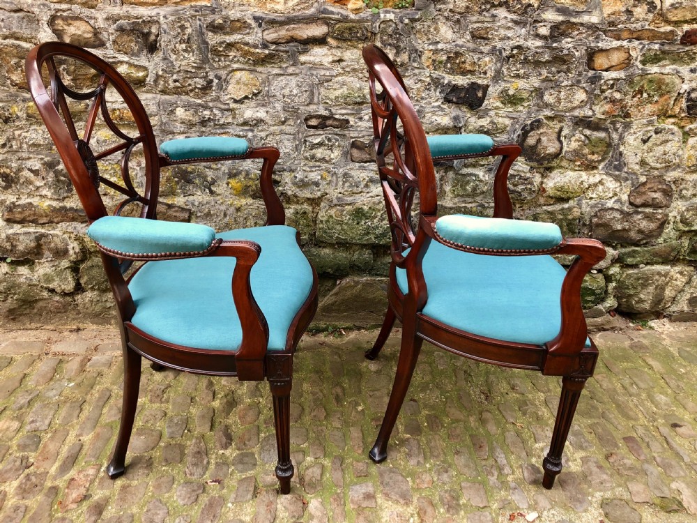 Pair of Sheraton Revival mahogany elbow chairs with oval wheel-back splats, carved rosettes, turquoise velvet seats, and turned reeded front legs. View II