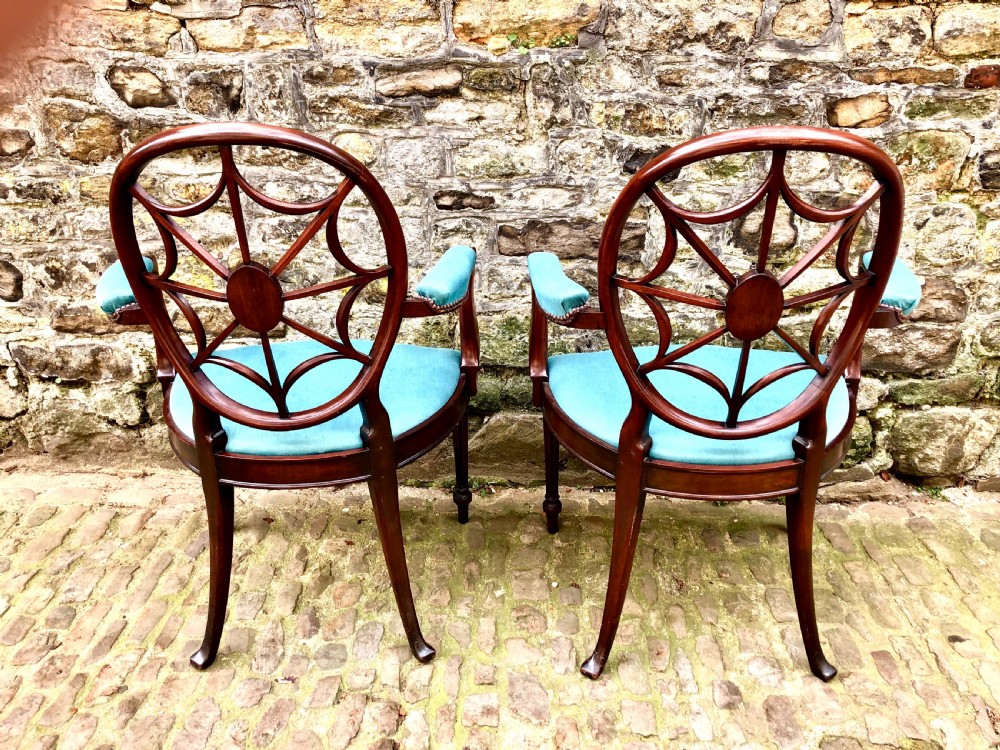 Pair of Sheraton Revival mahogany elbow chairs with oval wheel-back splats, carved rosettes, turquoise velvet seats, and turned reeded front legs. View V