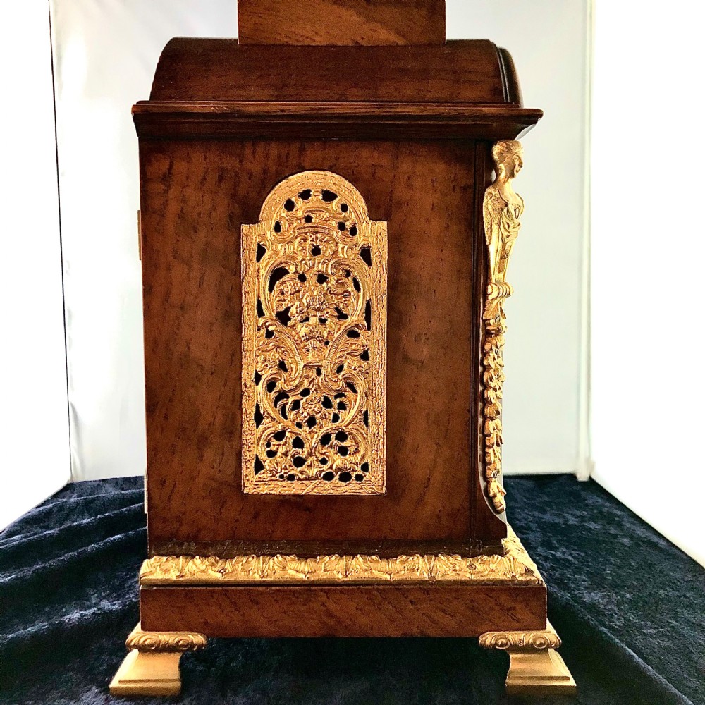 A late 19th-century mahogany bracket clock featuring an arched silvered dial, gilt-bronze caryatid mounts, and a brass finial top. View VI