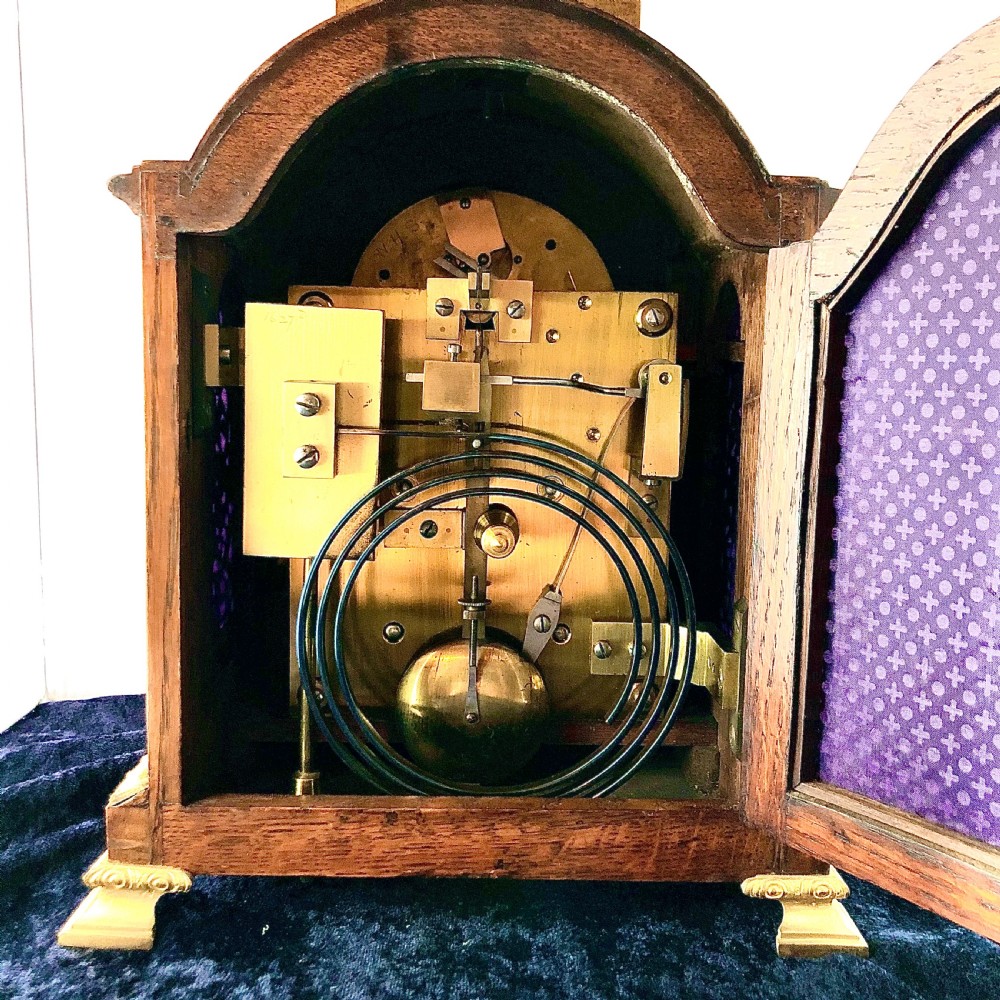 A late 19th-century mahogany bracket clock featuring an arched silvered dial, gilt-bronze caryatid mounts, and a brass finial top. View VIII