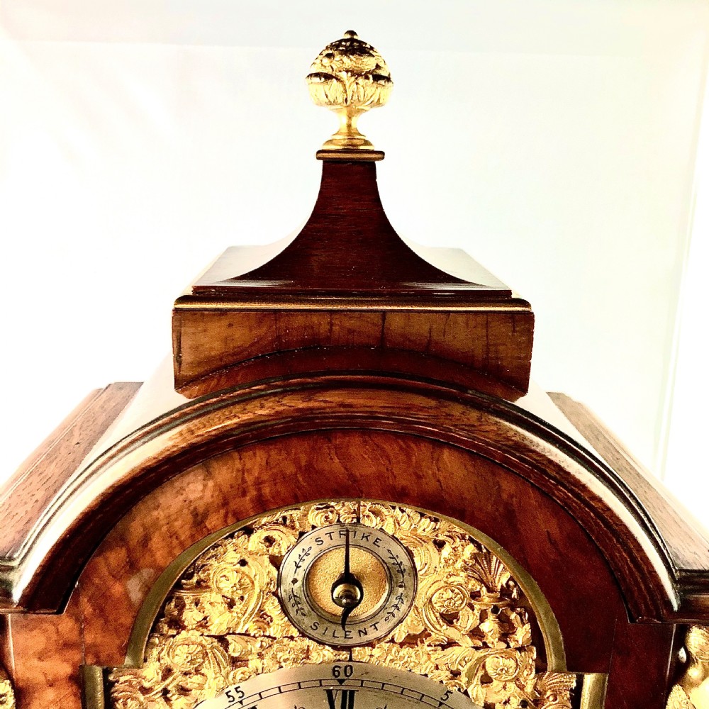 A late 19th-century mahogany bracket clock featuring an arched silvered dial, gilt-bronze caryatid mounts, and a brass finial top. View IX