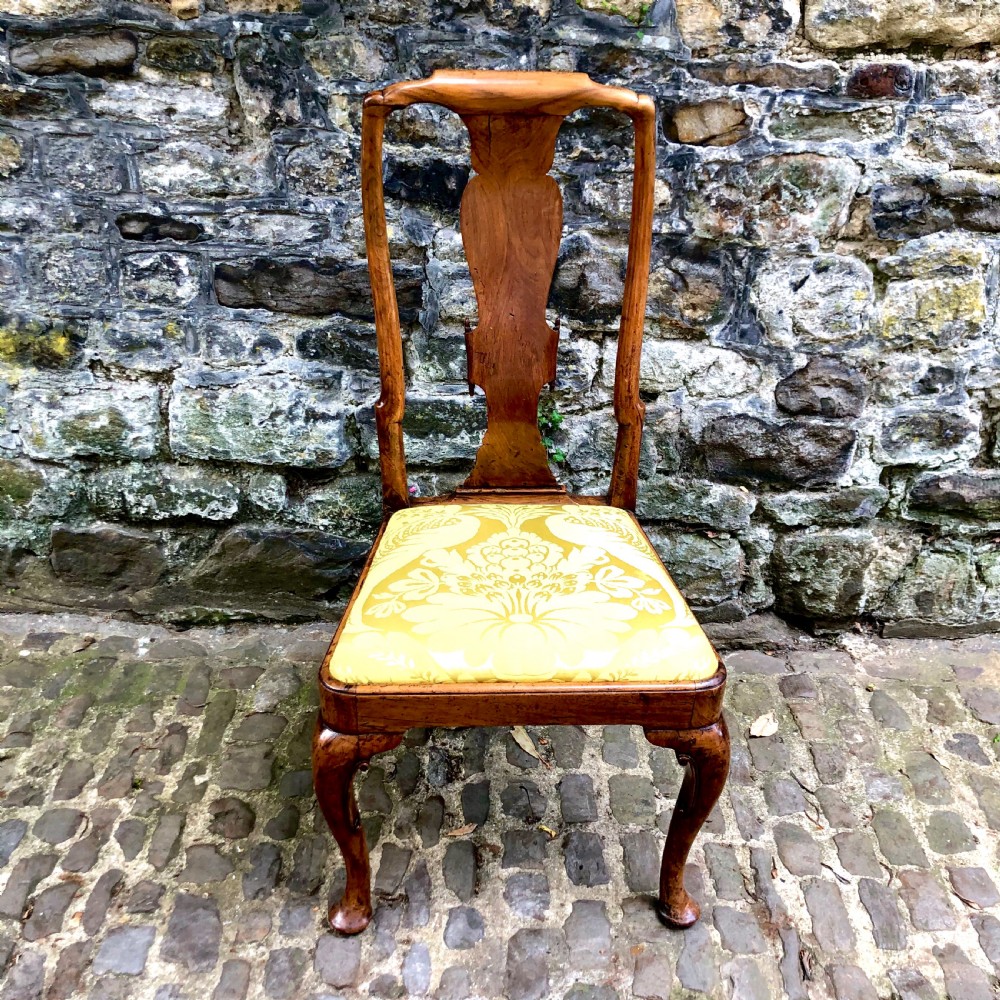 A Queen Anne walnut side chair featuring a vasiform back splat, cabriole front legs with pad feet, and a yellow patterned silk upholstered seat.