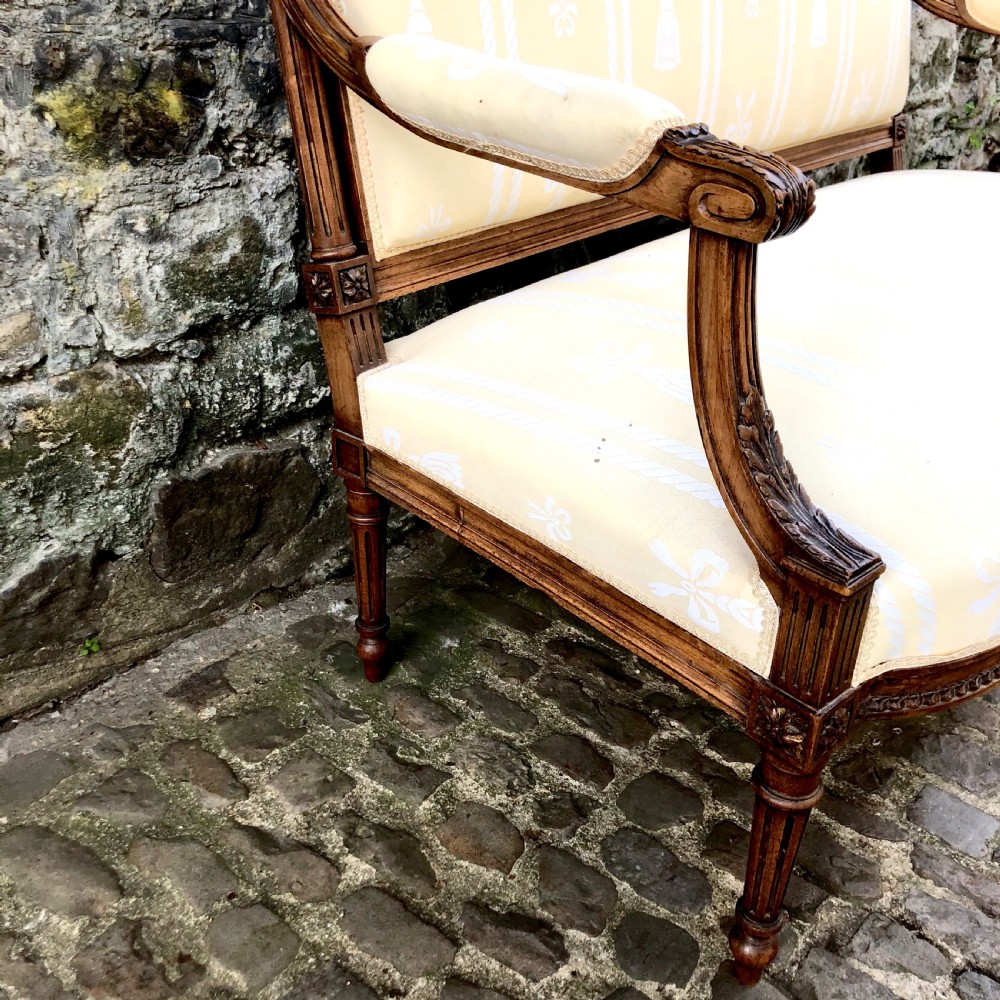 A French Second Empire carved walnut sofa featuring a cream and pale yellow striped upholstered back and seat with padded armrests and fluted legs. View II