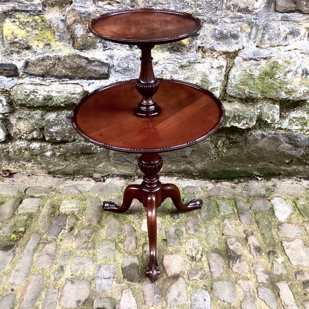 A late nineteenth-century mahogany two-tier wine table featuring two rounded circular trays on a central turned stem supported by a tripod base.