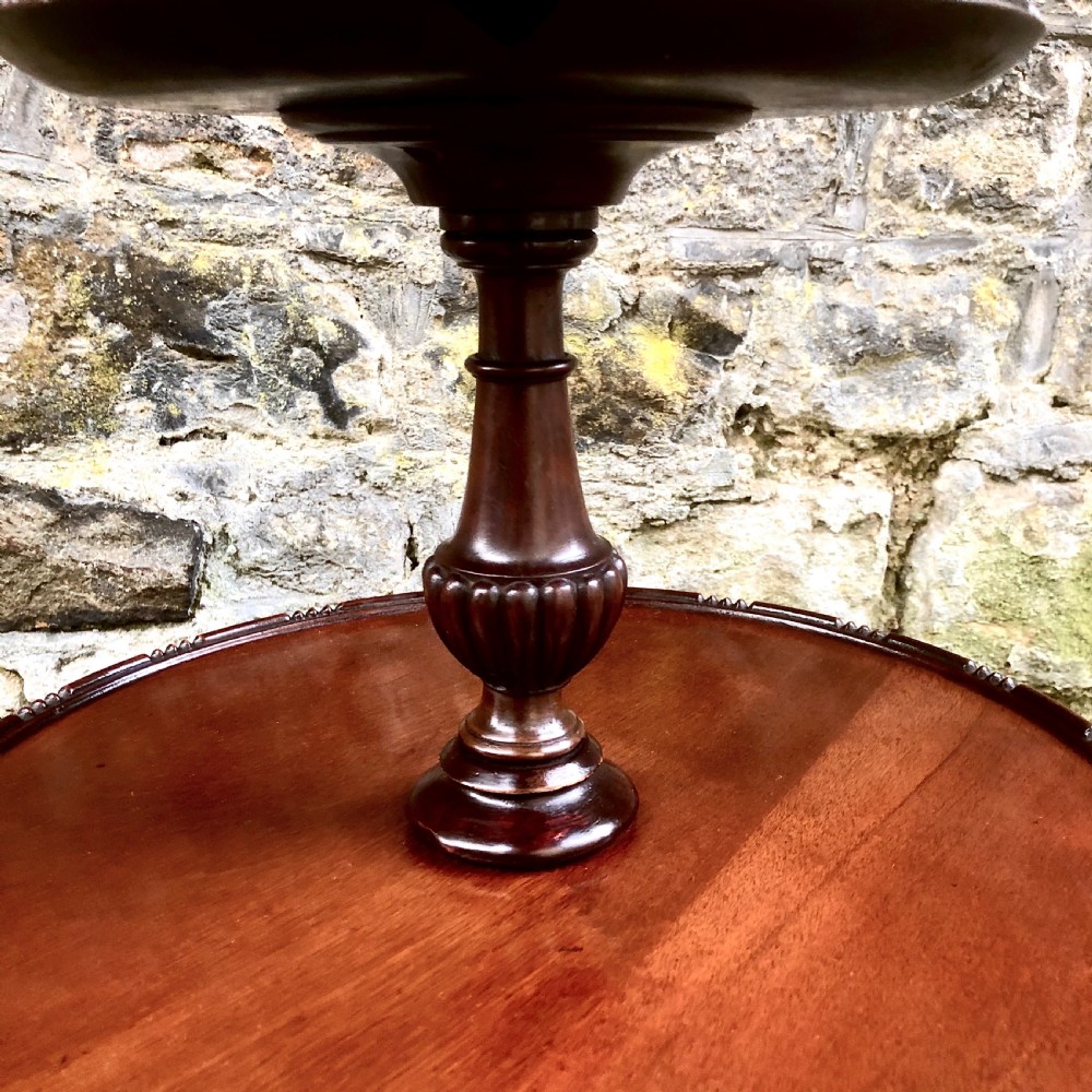 A late nineteenth-century mahogany two-tier wine table featuring two rounded circular trays on a central turned stem supported by a tripod base. View IV