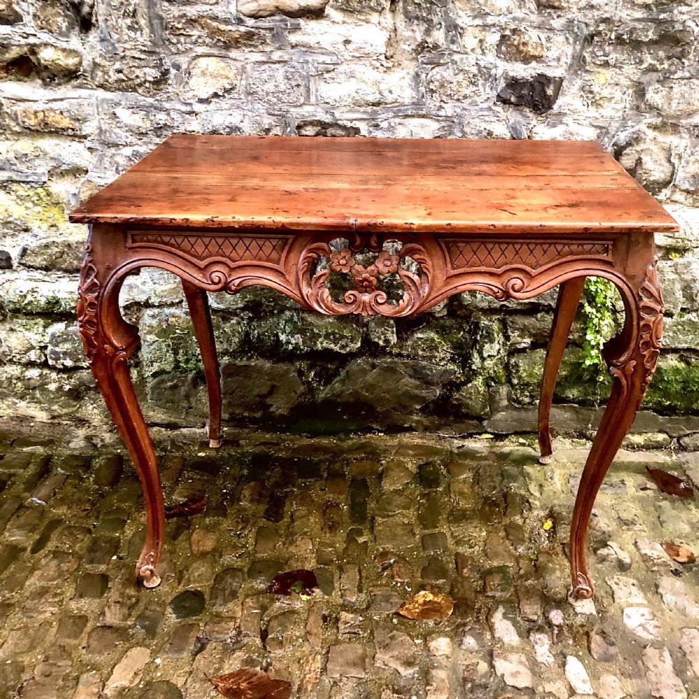 A French Louis XV style carved walnut centre table featuring cabriole legs and a decorative floral apron.