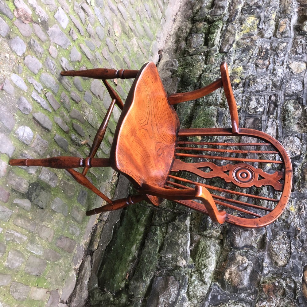An early nineteenth-century wooden Windsor armchair featuring a shaped elm saddle seat, turned legs, curved armrests, and a pierced central splat. View II