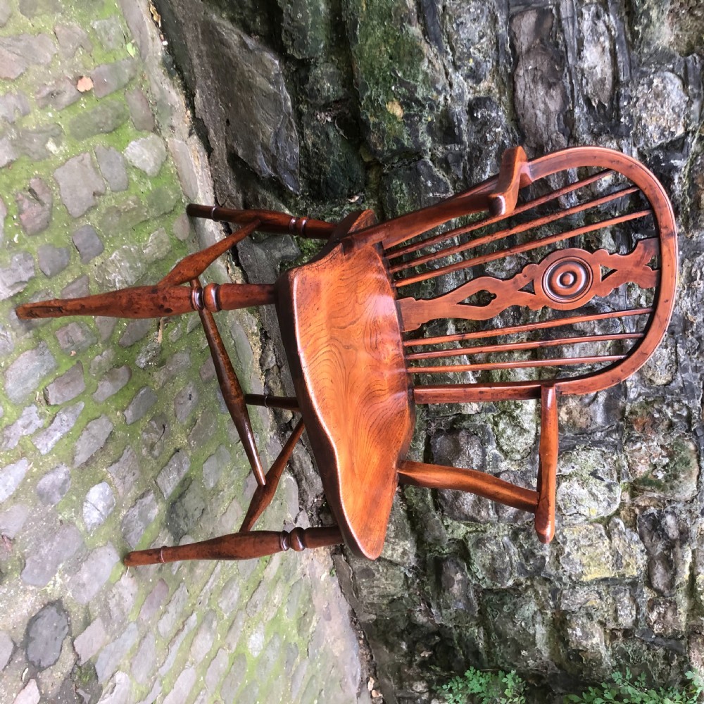 An early nineteenth-century wooden Windsor armchair featuring a shaped elm saddle seat, turned legs, curved armrests, and a pierced central splat. View III