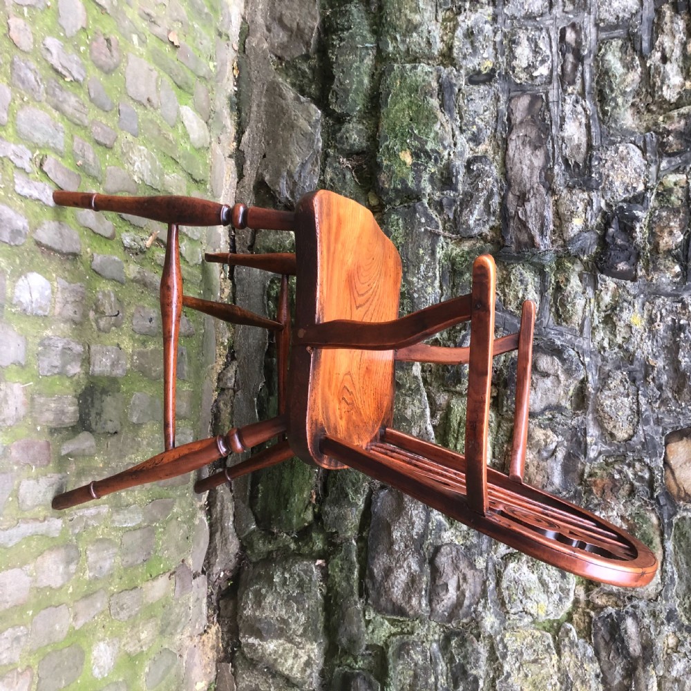An early nineteenth-century wooden Windsor armchair featuring a shaped elm saddle seat, turned legs, curved armrests, and a pierced central splat. View VI