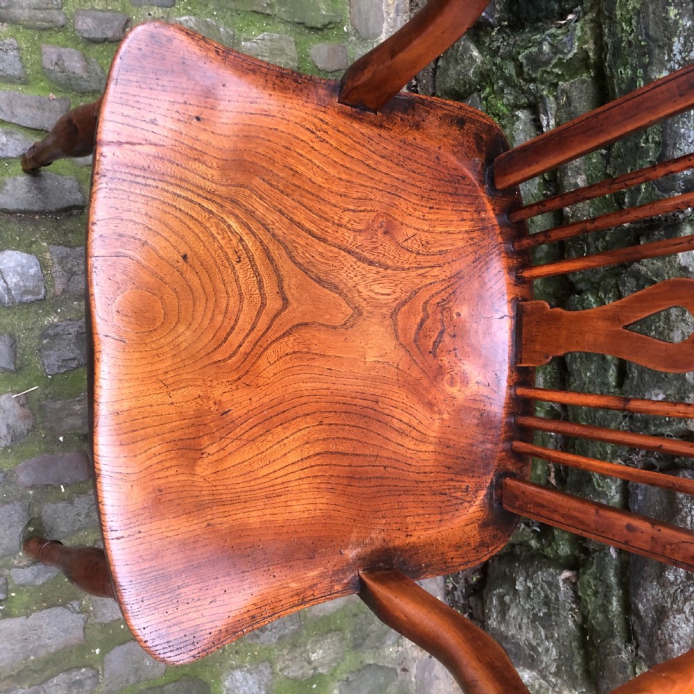 An early nineteenth-century wooden Windsor armchair featuring a shaped elm saddle seat, turned legs, curved armrests, and a pierced central splat. View VIII