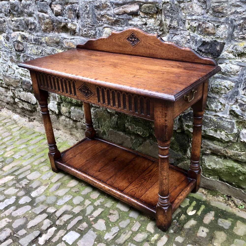 An early twentieth-century carved dark oak hall table featuring a splashback with a carved floral medallion, arcaded frieze, turned legs, and a lower shelf. View II