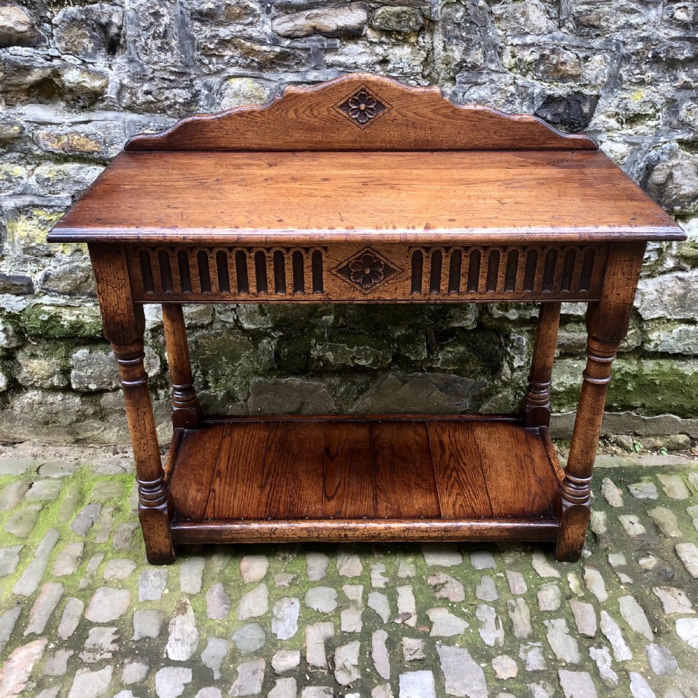 An early twentieth-century carved dark oak hall table featuring a splashback with a carved floral medallion, arcaded frieze, turned legs, and a lower shelf. View III
