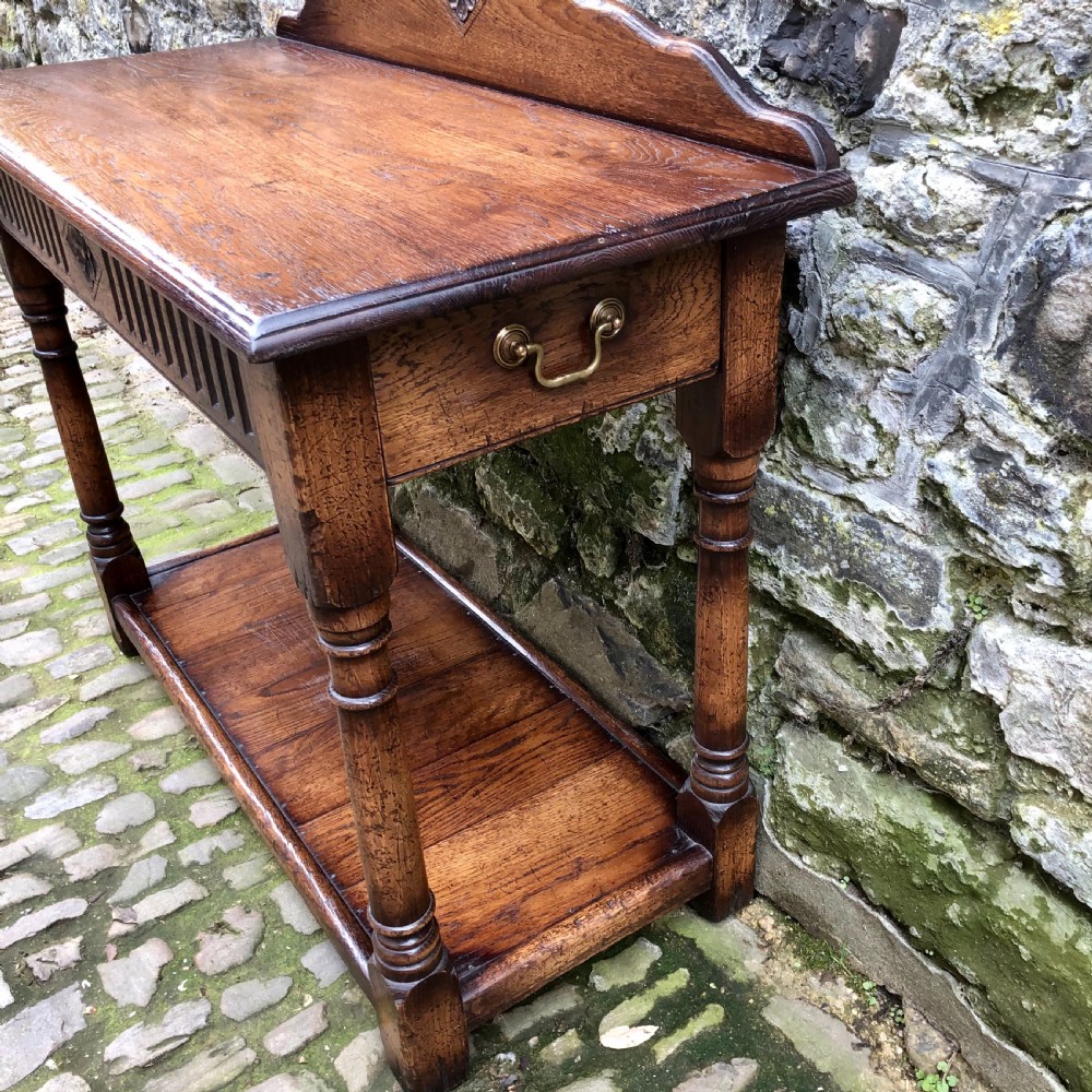 An early twentieth-century carved dark oak hall table featuring a splashback with a carved floral medallion, arcaded frieze, turned legs, and a lower shelf. View IV
