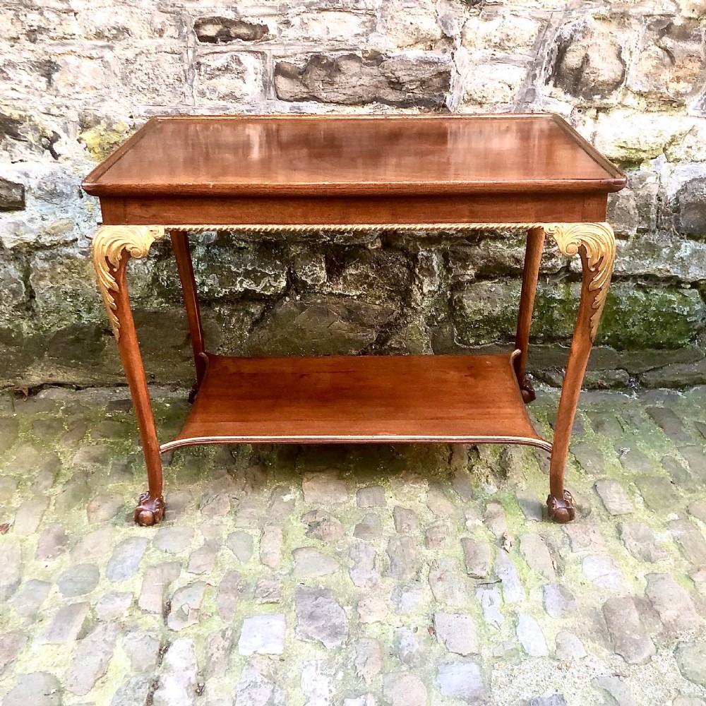 A late nineteenth-century two-tier walnut coffee table featuring carved gilded cabriole legs and a polished lower shelf.