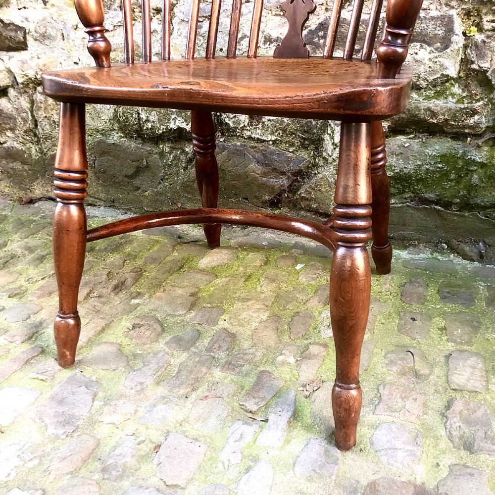 A mid-Victorian yew wood Windsor armchair featuring a hoop back, pierced central splat, turned legs, and a shaped wooden seat. View IV
