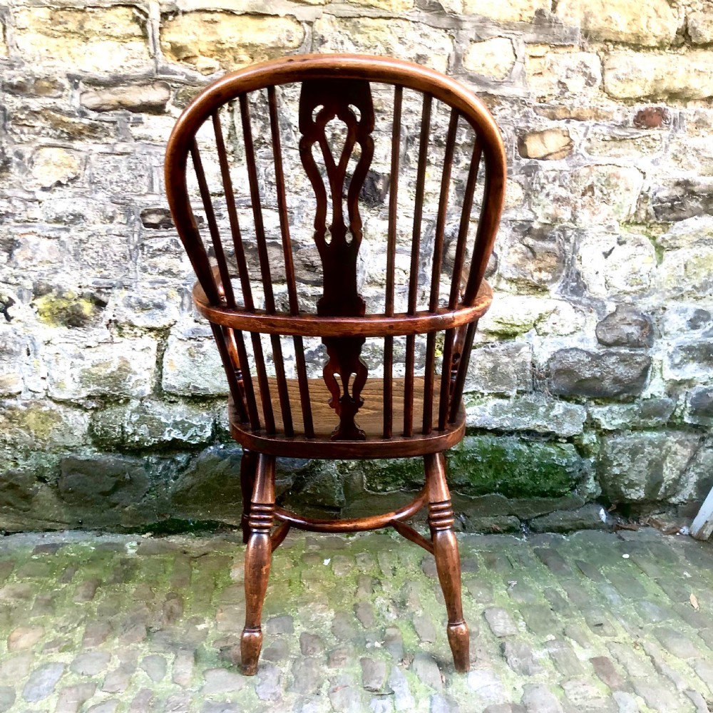 A mid-Victorian yew wood Windsor armchair featuring a hoop back, pierced central splat, turned legs, and a shaped wooden seat. View V