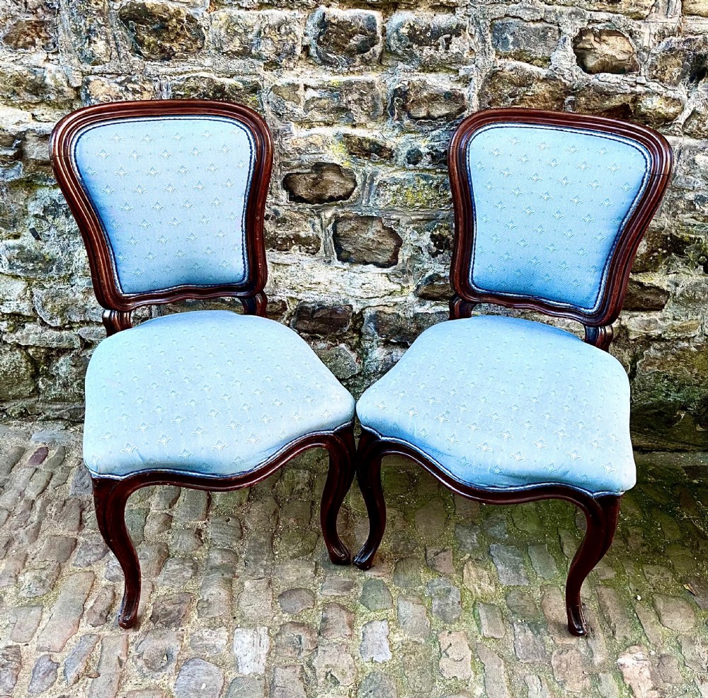A set of four mid-19th century Louis XV style dining chairs featuring carved dark wood frames, cabriole legs, and light blue patterned fabric upholstery. View II