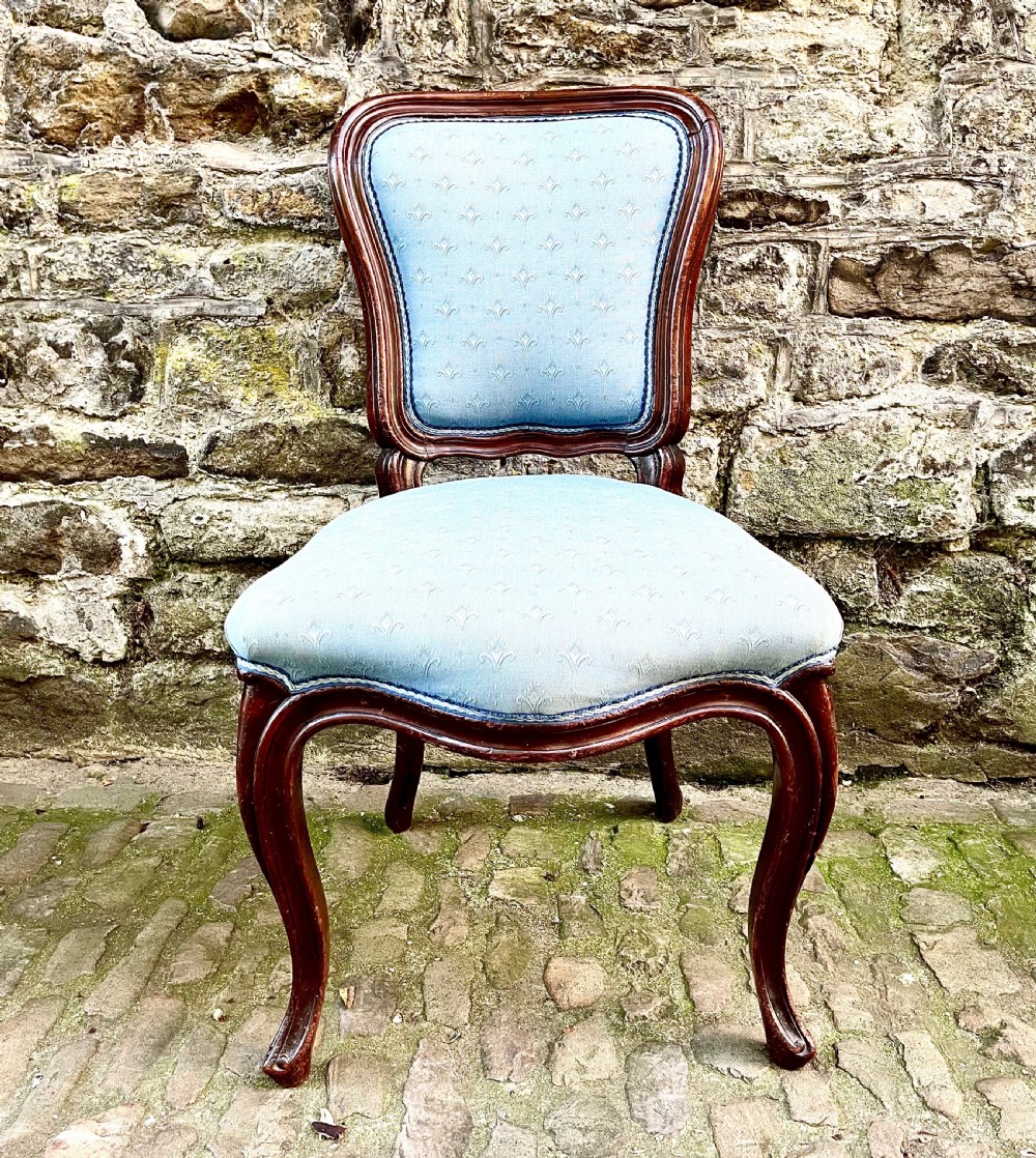 A set of four mid-19th century Louis XV style dining chairs featuring carved dark wood frames, cabriole legs, and light blue patterned fabric upholstery. View IV