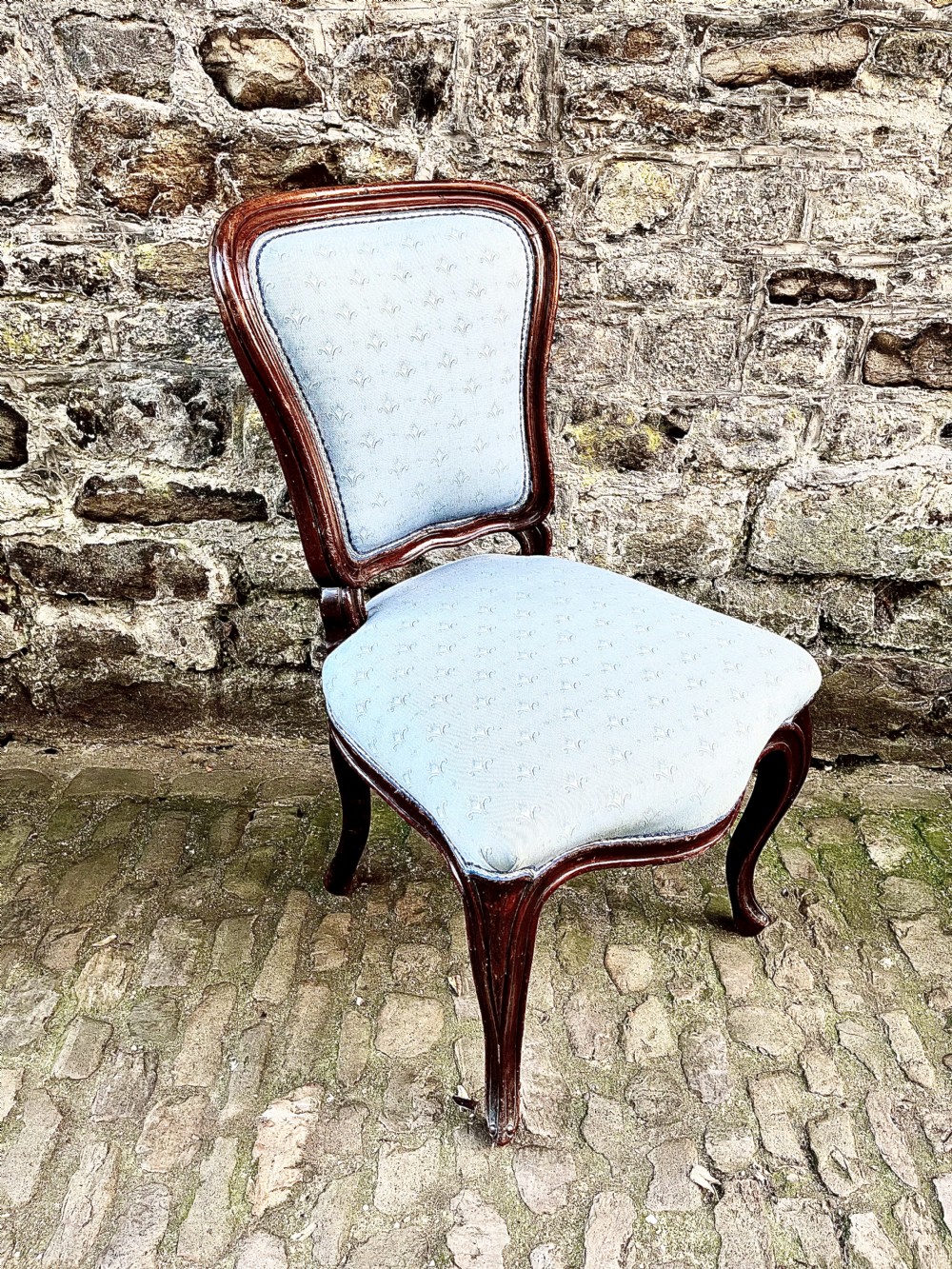 A set of four mid-19th century Louis XV style dining chairs featuring carved dark wood frames, cabriole legs, and light blue patterned fabric upholstery. View V